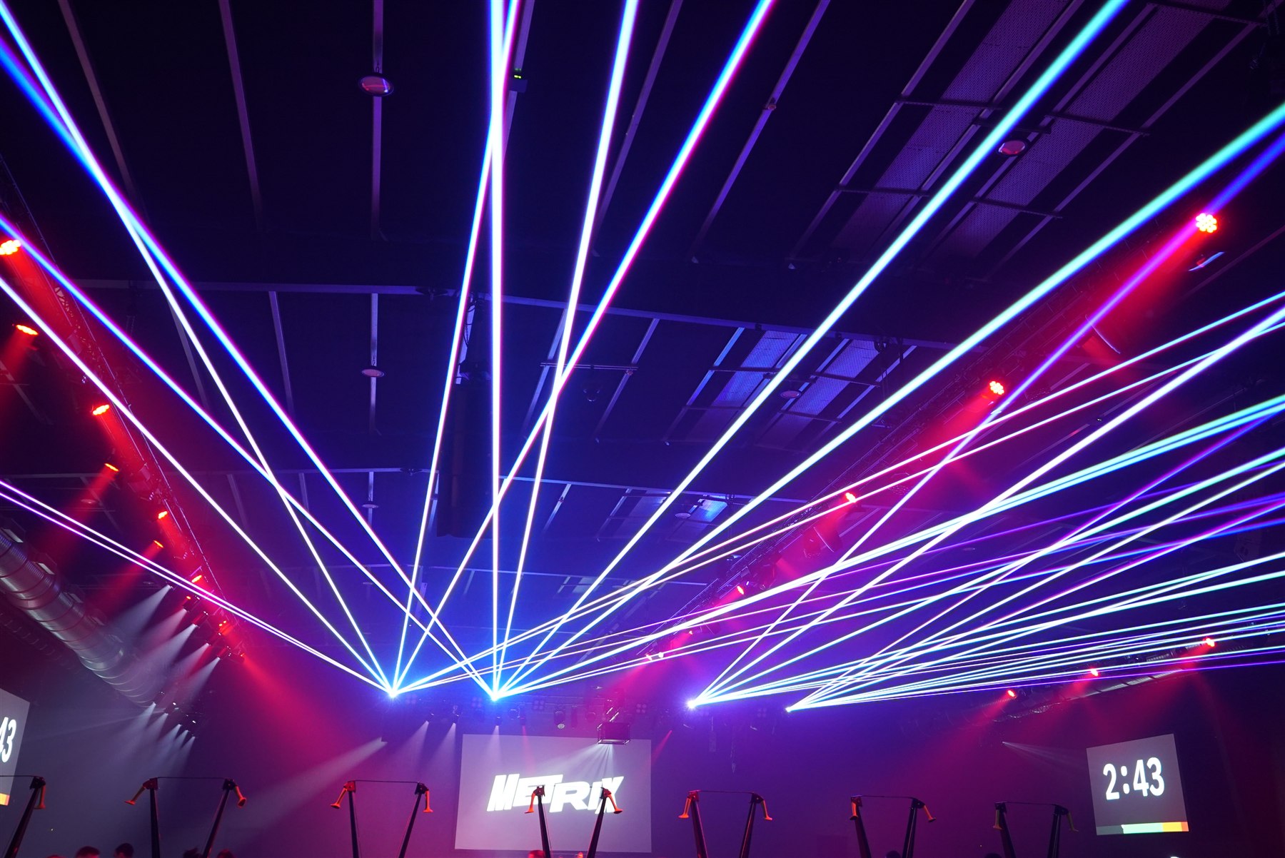Blue, violet and white laser beams across the ceiling of an indoor event space