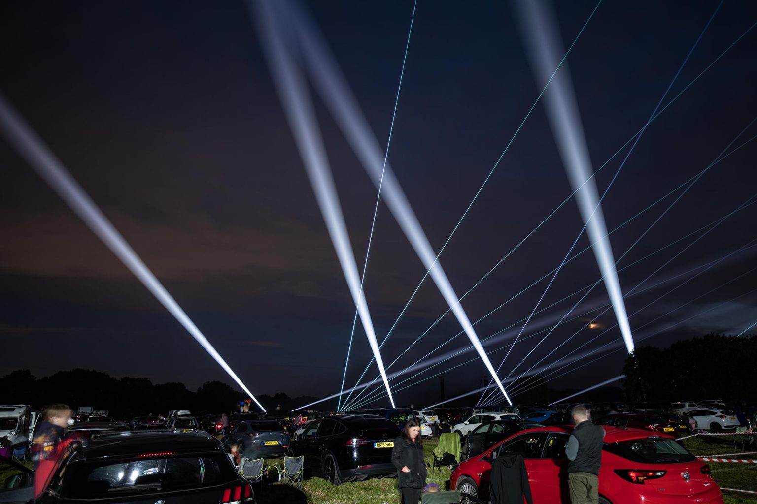 Outdoor laser beams and searchlights above an event audience
