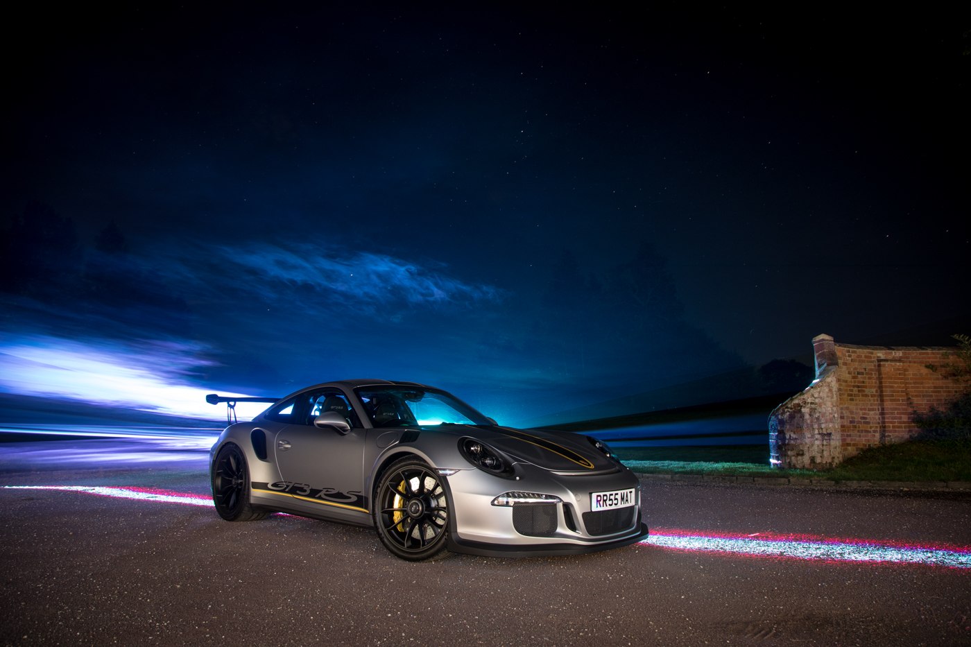A silver Porsche surrounded by blue laser beams outdoors at night